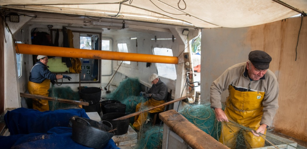 Pescadors reparant les xarxes d'arrossegament, una de les modalitats afectades per les vedes temporals que regulen l'activitat pesquera al litoral català